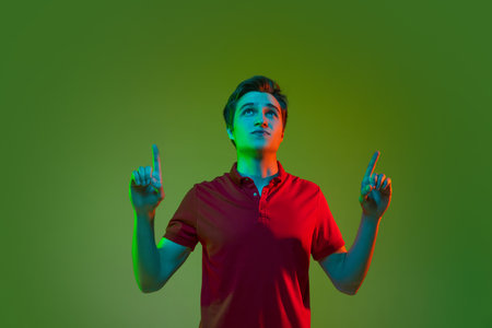 One young caucasian man in casual clothing isolated on green neon background. Concept of human emotions, facial expression.の写真素材