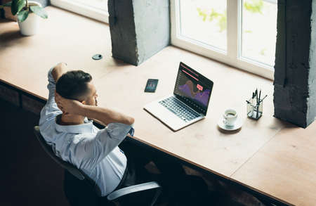 Comparison of graphs. One young businessman, office worker with laptop. Business, working process concept. View from aboveの写真素材