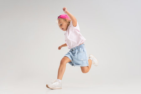 Studio image of little preschool Caucasian girl in casual clothes running, jumping isolated over white studio background.の写真素材