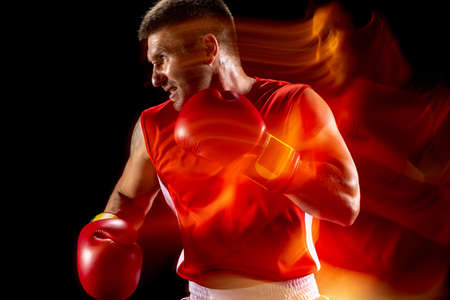 Cropped portrait of professional male boxer training on black studio background in mixed lights. Red and blackの写真素材