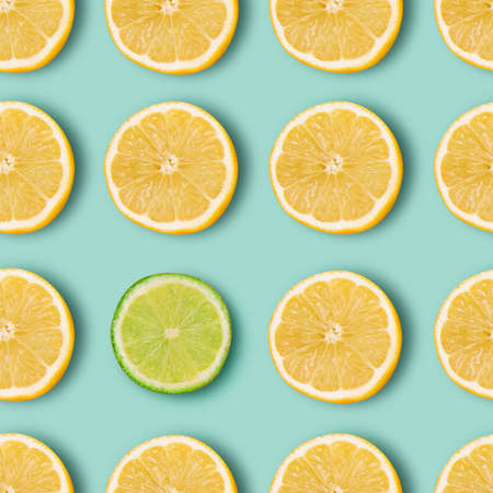 Unlike the others. Halves of juicy yellow lemons and one lime arranged over vibrant light blue background.の写真素材