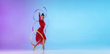 Flyer. Portrait of female rhythmic gymnast in red dress exercising with bright ribbon isolated on...