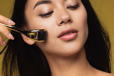 Studio image of beautiful female face isolated on yellow studio background. Close-up portrait