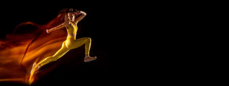 Young woman, female athlete training isolated over black studio background in mixed neon lights. Flyerの写真素材