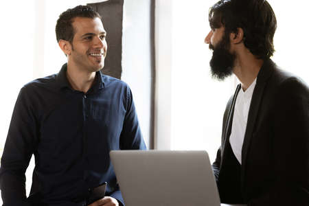 Young men working in modern office using devices and gadgets. Making reports, analitycs, routine processing tasksの写真素材