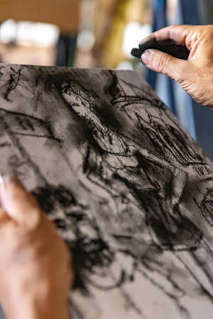 Close up of artists hand painting with graphite crayonの写真素材