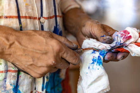 Closeup of hand mixing paint on palette at workshopの写真素材