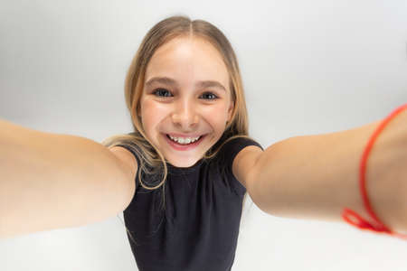 Showing device screen. One little screaming school girl holding smartphone isolated over white studio background.の写真素材
