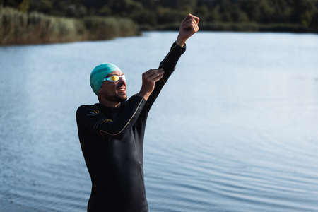 Professional triathlete before swimming in rivers open water. Man wearing swim equipment practicing...