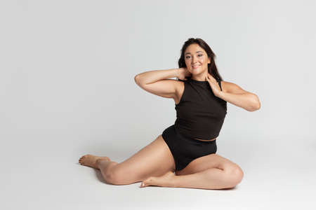 Young beautiful plump woman in cotton underwear on white background