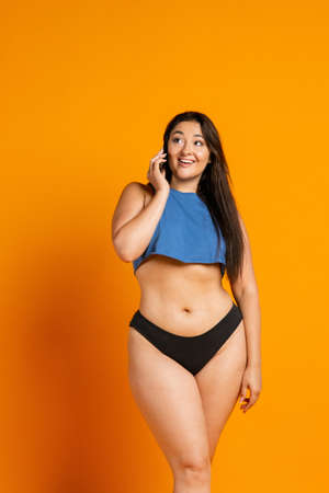 Young beautiful plump woman in cotton underwear on orange backgroundの写真素材