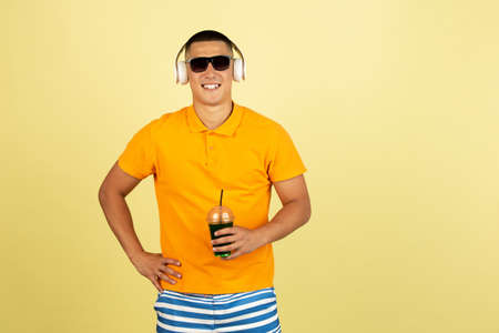 Summer mood. Portrait of young handsome asian man in summer clothes with white headphones and...