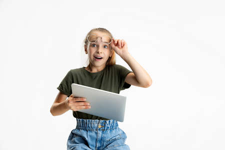 One smart teen school caucasian girl in casual clothes and glasses holding tablet isolated over...