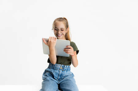 One smart teen school caucasian girl in casual clothes and glasses holding tablet isolated over...