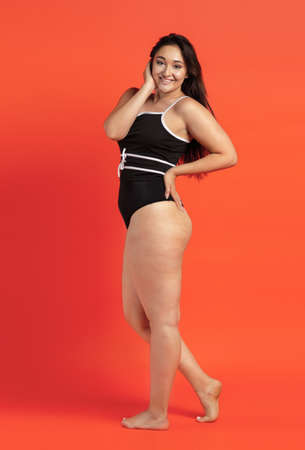 Young beautiful plump woman in black underwear on orange backgroundの写真素材