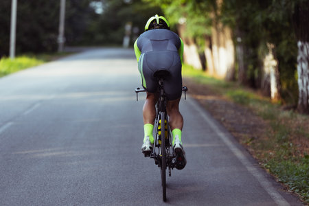 Young male triathlete riding a bicycle on the open road. Professional sportsman is engaged in triathlon on bright summer dayの写真素材