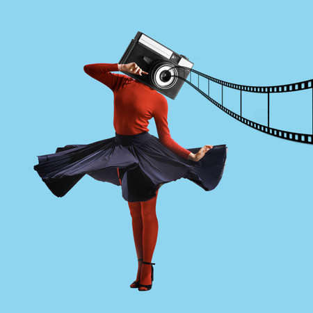 Surrealism. Young woman headed with retro-style camera in colored clothes stands over blue backgroundの写真素材