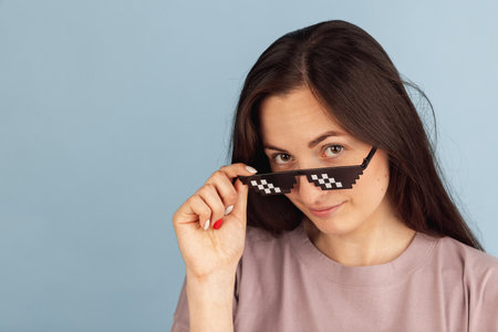 One young Caucasian woman in stylish eyeglasses posing isolated on blue background.