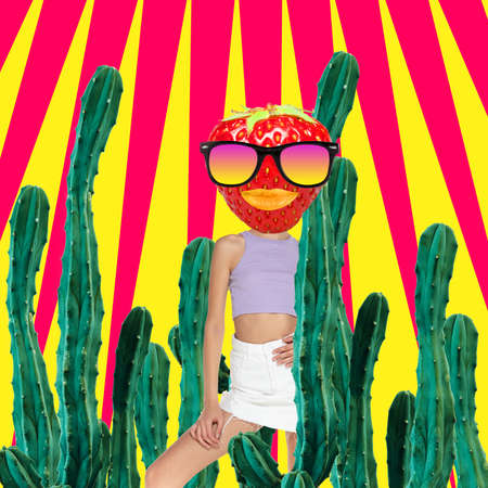 Funny artwork. Young woman headed with strawberry in glasses standing among huge cactus. Surreal compositionの写真素材