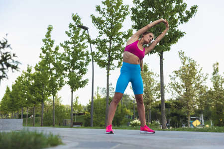 Young slim sportive caucasian woman working out, doing fitness, yoga in the park or on city street.の写真素材