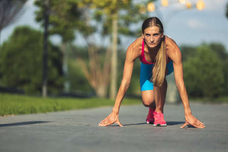 Young slim sportive caucasian woman working out, doing fitness in the park or on city street.の写真素材