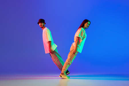 Two young people, guy and girl in casual clothes dancing contemporary dance, hip-hop over blue...