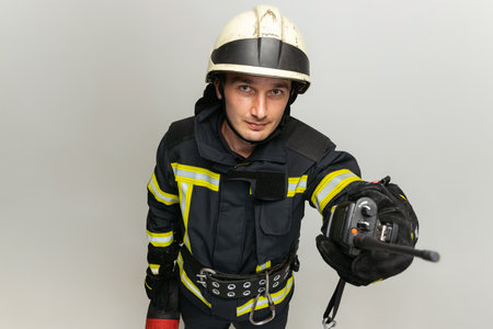 One male firefighter dressed in uniform posing over white studio background.の写真素材