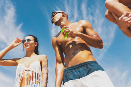 Young people, men and women swimsuit resting on the beach, having fun, sunbathingの写真素材
