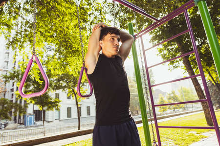 One young handsome caucasian man in sportswear training, exercising on crossfit ground outdoors on...