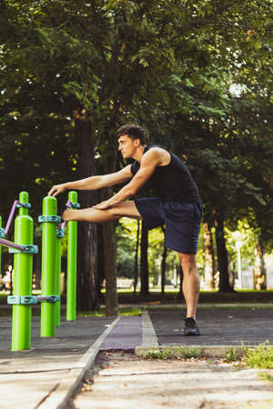 One young handsome caucasian man in sportswear training, exercising on crossfit ground outdoors on bright summer day.の写真素材