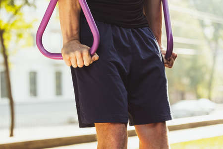 One young handsome caucasian man in sportswear doing crossfit at sports ground on bright summer day....