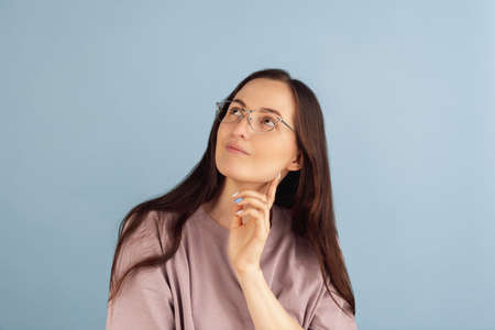 Close-up. Portrait of young Caucasian woman posing isolated on blue studio background.