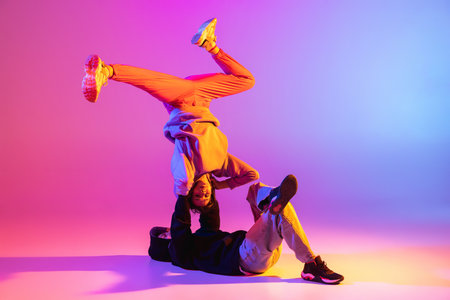 Two young people, guy and girl in casual clothes dancing contemporary dance, hip-hop over pink...