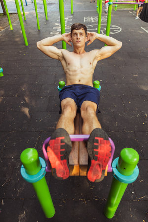 One young handsome caucasian man in sportswear training, exercising on sports ground outdoors on bright summer day.の写真素材