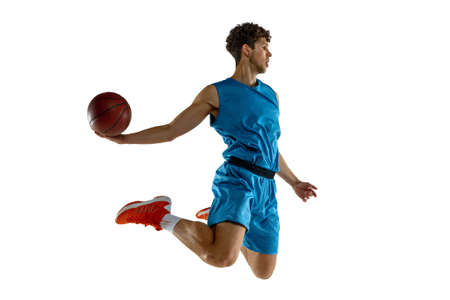 Side view. Young caucasian professional basketball player exercising with ball isolated on white...