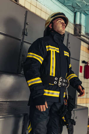 One male firefighter dressed in uniform with protective helmet at fire stationの写真素材