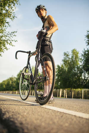 Young male cyclist with road bike in summer day. Action, motion concept. Full length.の写真素材