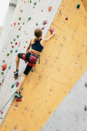 One cute teen girl practicing on the rock wall in climbing center. Concept of sportive lifestyle,...