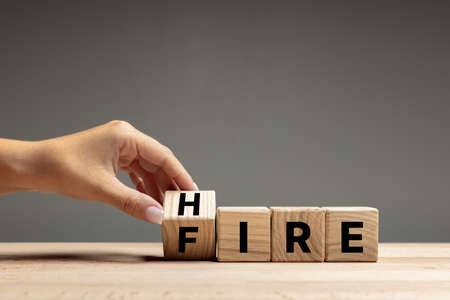 Female hand fliping wooden cubes with word hire to fire. Business strategy concept. Copyspace for ad.の写真素材