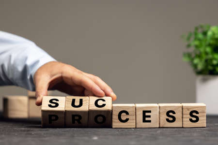 Male hand fliping wooden cubes with word process to success. Copyspace for ad, offer.の写真素材