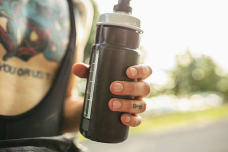 Close-ip hand of a young sportive male cyclist holding water bottleの写真素材