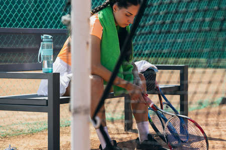 Professional female tennis player sitting on bench on tennis courtの写真素材
