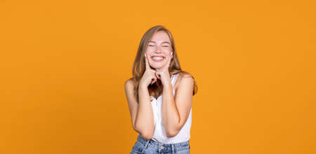 Keep smiling. Cheerful young girl smiling on orange bakgroundの写真素材