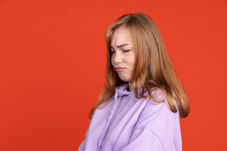 Half-length portrait of young girl pouting her lips isolated on red studio background. Concept of human emotionsの写真素材