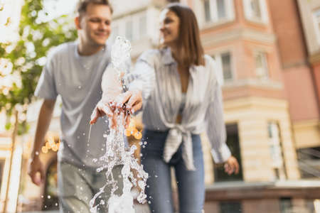 Blurred photo of young couple having fun near fountain outdoors on warm summer day