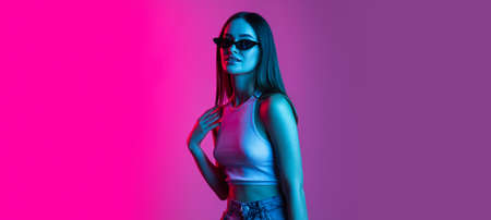 Beautiful young girl wearing glasses isolated on gradient pink purple background
