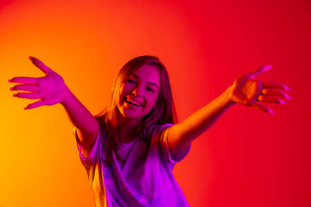 Portrait of young beautiful caucasian girl isolated on pink neon backgroundの写真素材