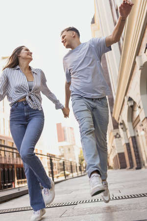 Full-length portrait of young happy couple in motion. Walking around city on warm sunny dayの写真素材