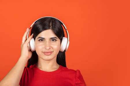 Portrait of young beautiful girl in headphones isolated over orange background.の写真素材