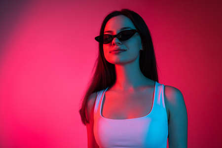 Cropped studio portrait of young beautiful caucasian girl on gradient pink red backgroundの写真素材